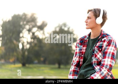 Portrait woman with short hair wearing plaid shirt and headphones outdoors. Stock Photo