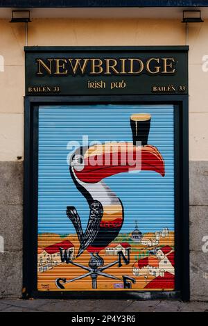 Madrid, Spain - November 1, 2020: Locked roll-up door painted with the image of a toucan from an Irish pub called Newbridge Stock Photo