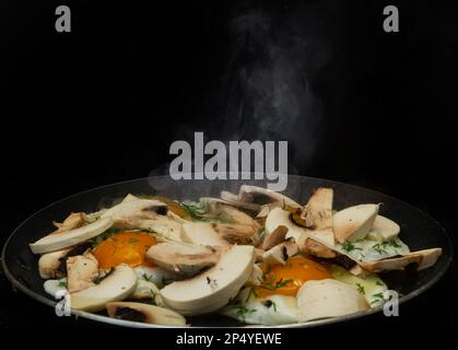 Fried mushrooms and eggs in a pan. The process of cooking breakfast. Close up. Stock Photo