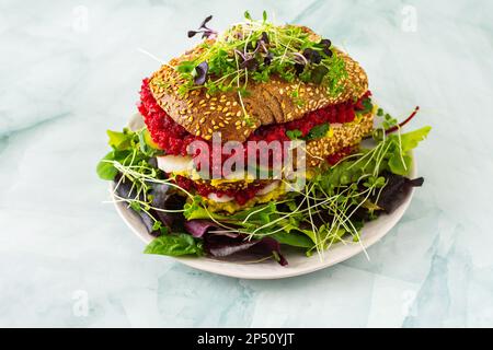 Sandwiches with avocado, radish and cucumbers, grated beetroot on a mix salad with microgreens , sandwiches on a plate on a marble green background Stock Photo