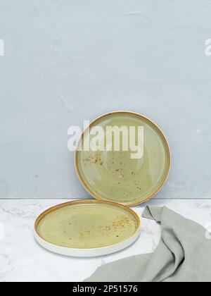 Set of two empty green plates with tablecloth on white marble table with gray background. Handmade ceramic plates Stock Photo