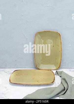 Set of two rectangular green plates with tablecloth on white marble table with gray background Stock Photo