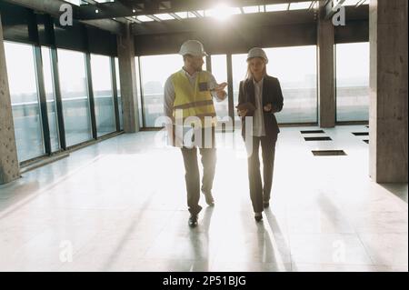 Architects on construction. a girl and a male engineer are walking and looking at a project, Stock Photo