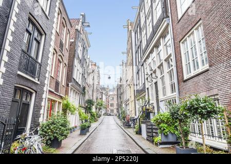 Amsterdam, Netherlands - 10 April, 2021: an old street in amsterdam, the netherlands with bikes parked on both sides and potted planters along the side Stock Photo
