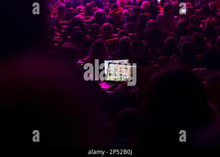 Auditorium seat in the theather. Soundman on the mixing console during a concert. Soundman working on the mixing console in concert hall. Out of focus Stock Photo