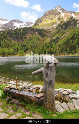Watering Place, tree trunk wooden water fountain on hiking trail to mountain lake Duisitzkar, Styria - Austria Stock Photo