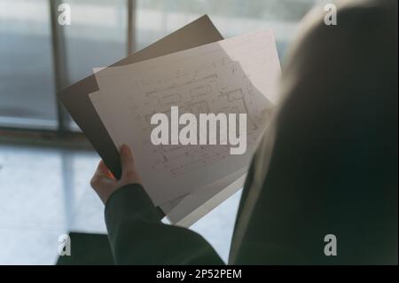 the architect girl holds a paper with a drawing in her hand. Stock Photo