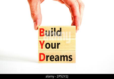 BYD build your dreams symbol. Concept words BYD build your dreams on wooden blocks on a beautiful white table white background. Businessman hand. Busi Stock Photo