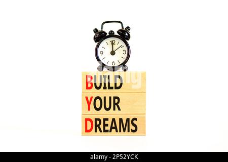 BYD build your dreams symbol. Concept words BYD build your dreams on wooden blocks on beautiful white table white background. Black alarm clock. Busin Stock Photo