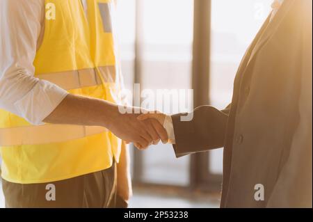 Close up engineer shake hand on site construction. handshake at sunset Stock Photo