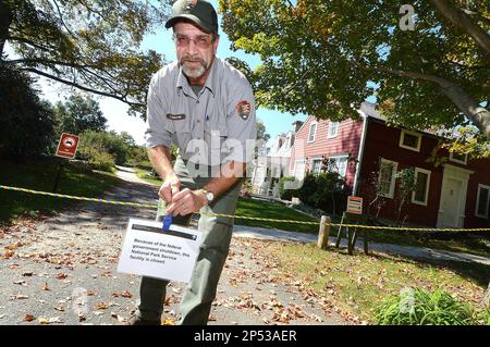 Weir Farm National Historic Site Facility Manager Kevin Monthie places a sign on a rope strung accross the entrance to the Park in Wilton, Conn., stating the National Park service facility is closed due to the Federal Government shutdown on Tuesday Oct. 1, 2013. (AP Photo/The Hour, Alex von Kleydorff)