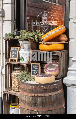 Various Dutch cheeses displayed on a wooden box and a wooden rain barrel outside on the street in front of a cheese shop Stock Photo
