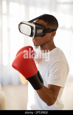 Portrait of black guy working out boxing in VR headset Stock Photo