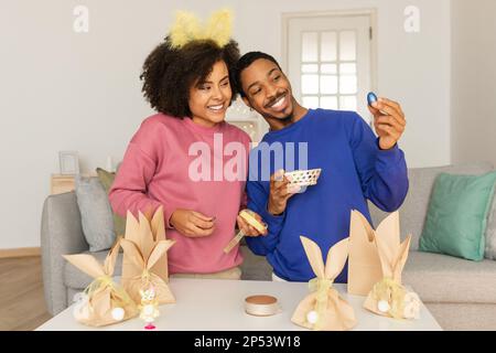 Smiling African American Couple Holding Easter Chocolate Egg At Home Stock Photo
