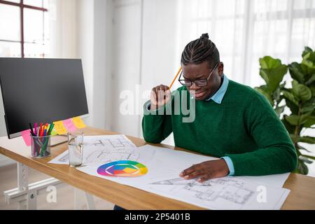 Pensive Black Engineer Man Making Technical Drawing Of Object Indoor Stock Photo