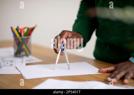 Unrecognizable Black Man Drawing Using Compass Tool Working Indoors, Cropped Stock Photo