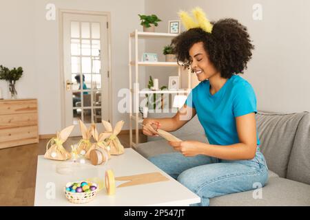 Happy black woman making handmade easter gift packaging at home Stock Photo