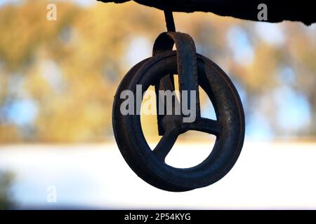 Old iron pulley to draw water from a well with a bucket and rope Stock Photo
