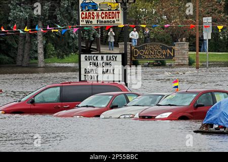 Floodwaters partially submerge vehicles in a used car lot in