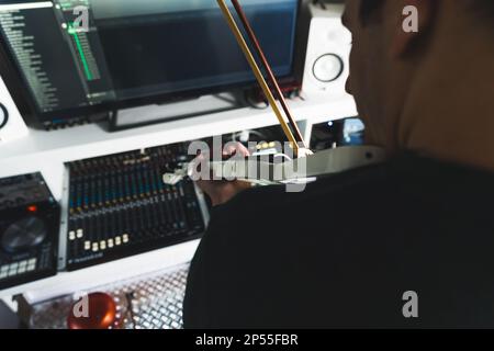 man playing the violin in his home recording studio, back view closeup shot music concept. High quality photo Stock Photo