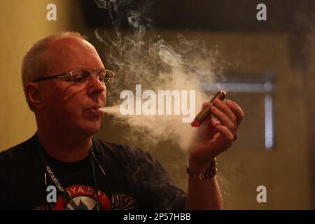 In this photo taken Friday, August 2, 2013, Tim Mahoney, a tobacco  connoisseur from Knoxville, puffs out smoke after lighting a cigar while at  the Burn's Tobacconist's Tweetup and Cigar Festival in
