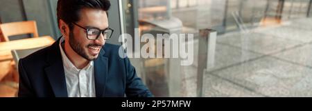 Indian businessman is making notes in notepad during working day in cafe. Blurred background Stock Photo