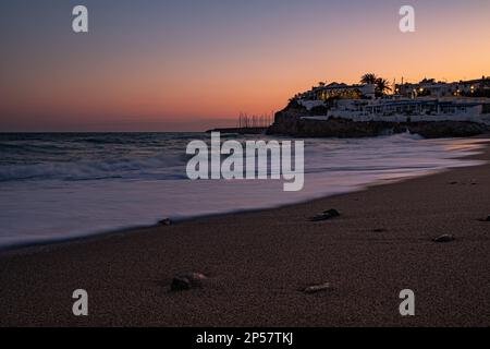 Beach and calm sea at sunset with golden, purple and red sky.A journey along the Catalan coast of Spain.Garraf beach at sunset, mediterranean seascape Stock Photo