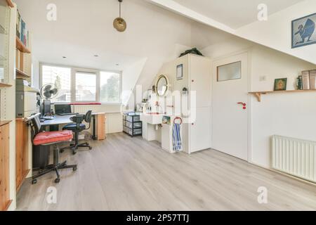 a home office with wood flooring and white walls in the room is well lit by the light coming through the window Stock Photo