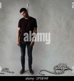 Depressed man with rope noose on neck against light grey background Stock Photo