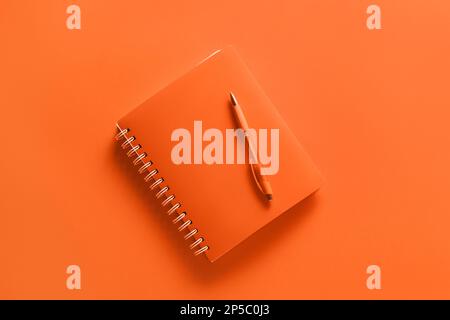 Notebook with pen on orange background Stock Photo