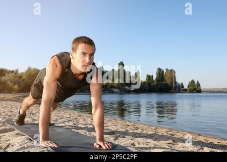 Sporty man doing straight arm plank exercise on beach Stock Photo