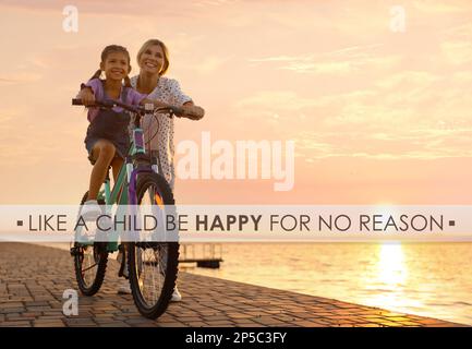 Like A Child, Be Happy For No Reason. Inspirational quote saying that you don't need anything to feel happiness. Text against mother teaching daughter Stock Photo