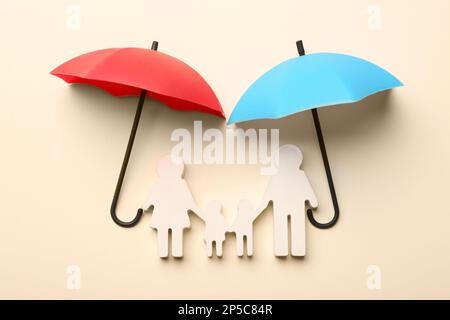 Mini umbrellas and family figure on beige background, flat lay Stock Photo