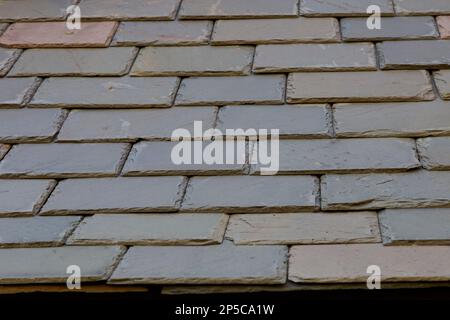 Slate siding tiles on the wall of a building in New England. There is a range of colors, textures, and rectangular shapes. Stock Photo
