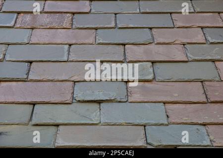 Slate siding tiles on the wall of a building in New England. There is a range of colors, textures, and rectangular shapes. Stock Photo