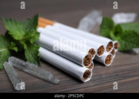 Cigarettes, menthol crystals and mint on wooden table, closeup Stock Photo