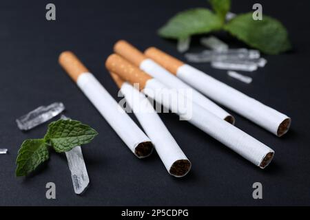 Cigarettes, menthol crystals and mint on black background, closeup Stock Photo