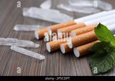 Cigarettes, menthol crystals and mint on wooden table, closeup Stock Photo