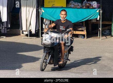 SAMUT PRAKAN, THAILAND, FEB 13 2023, A young man rides a motorcycle at market Stock Photo