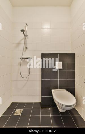 https://l450v.alamy.com/450v/2p5dx12/a-modern-bathroom-with-black-and-white-tiles-on-the-floor-shower-head-and-toilet-seat-in-the-corner-2p5dx12.jpg