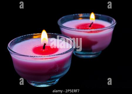 two burning candles placed on black background Stock Photo