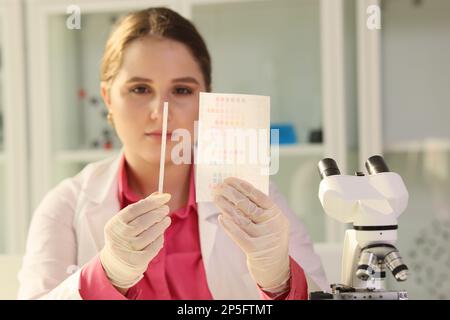 Scientist reviewing results of experiments and looking at paper with samples in research laboratory. Stock Photo