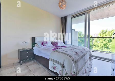 a bedroom with a bed, dresser and large sliding glass door that opens out onto the patio to the backyard Stock Photo