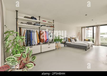 Amsterdam, Netherlands - 10 April, 2021: a bedroom with a bed and some clothes hanging on the wall next to an open door that leads to a balcony Stock Photo