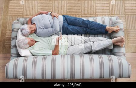 Retirement bliss. A senior couple lying on a couch together reading an e-book. Stock Photo
