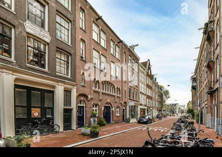 some bikes parked on the side of a street in an urban area with bricked buildings and shops along it Stock Photo