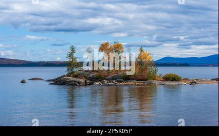 Small rocky island on Moosehead Lake. Trees in fall colors. Peak foliage in New England. Rockwood, Maine, US. Stock Photo