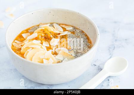 Chia pudding with passion fruit, coconut and coconut yogurt in white bowl. Healthy vegan recipe. Stock Photo