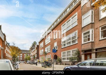 Amsterdam, Netherlands - 10 April, 2021: a city street with cars parked on the side and people walking down the street in the middle part of the street Stock Photo