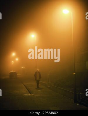 2021 04 03, Duisburg, Germany: A woman walking through thick fog at night Stock Photo